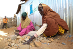 Kaksi naista halkoo kiviä Somaliassa.