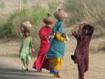 Naiset kantavat vesiruukkuja pään päällä.