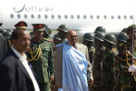 Sudanin presidentti Omar al-Bashir sotilaiden ympäröimänä, taustalla lentokone