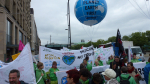 Mielenosoittajia bannerien ja ilmapallon kanssa Hampurissa