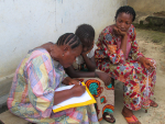 Opettaja seuraa kahden naisen lukemaan opettelua Sierra Leonessa