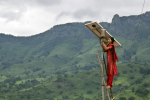 Nainen seisoo tikkailla ja asentaa aurinkopaneelia Intian vuoristossa.