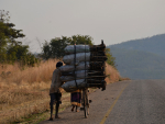 Mies työntää puuhiilikuormaa polkupyörällä Sambiassa