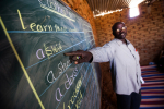Opettaja osoittaa liitutaulua Sudanissa
