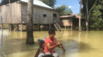 Mies meloo veneellä tulvan peittämässä kylässä