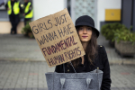 Nainen mielenosoituskyltin "Girls just wanna have fundamental human rights " kanssa