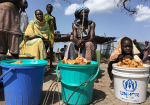Eteläsudanilaisia naisia ja lapsia myymässä ruokaa muoviämpäreistä