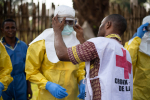 Punaisen Ristin avustustyöntekijä pukee ebolasuojavarusteita toiselle henkilölle Kongon demokraattisessa tasavallassa