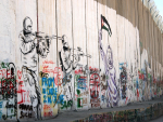 Seinämaalaus sotilaista tähtäämässä naista Betlehemissä.