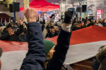 Mielenosoittajien käsiä pystyssä, taustalla Puolan lippu