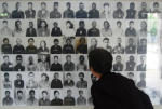 Mies katselee ihmisten kuvia seinällä punakhmerien hirmutekoja esittelevässä museossa