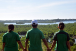 Kolme ihmistä selin kameraan käsi kädessä katsomassa mangrovemetsiä