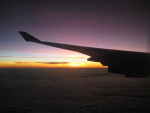 Lentokoneen siipi, taustalla auringonlasku