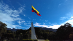 Kolumbian lippu veistoksen päässä, taustalla puita ja vuoria