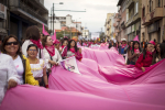 Pinkkiä lakanaa ja lippuja pitelevät naiset marssivat kadulla