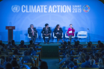 Neljä ihmistä istuu lavalla, Climate Action -teksti taustalla