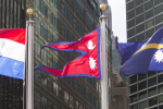 Nepalin lippu kahden muun lipun välissä, taustalla rakennuksia
