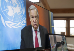 YK:n pääsihteeri tv-ruudulla YK:n lipun edessä.
