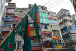 Kolme Bangladeshin lippua kerrostalon edustalla.