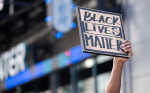 Ylös nostetussa kädessä oleva kyltti, jossa lukee Black Lives Matter.