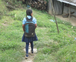 Takaapäin kuvattu tyttö koulureppu selässä.