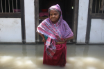 Nainen seisoo tulvavedessä rakennuksen edustalla.