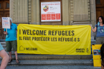 Keltainen mielenosoituskyltti, jossa lukee I welcome refugees, il faut protéger les réfugiées