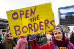 Mielenosoittaja ja kyltti, jossa lukee Open the borders.