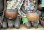 Polvillaan maassa istuvia lapsia, joilla on käsissään kulhoja.