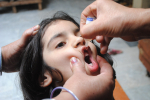 Aikuisen kädet pitelevät lapsen päätä paikallaan, toinen aikuinen antaa tälle suun kautta annettavan poliorokotteen.