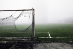 Jalkapallomaali, jossa riekaleinen verkko, sumuisella kentällä.