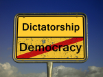 Kyltti, jossa lukee Dictatorship ja Democracy niin, että Democracy-sana on yliviivattu.